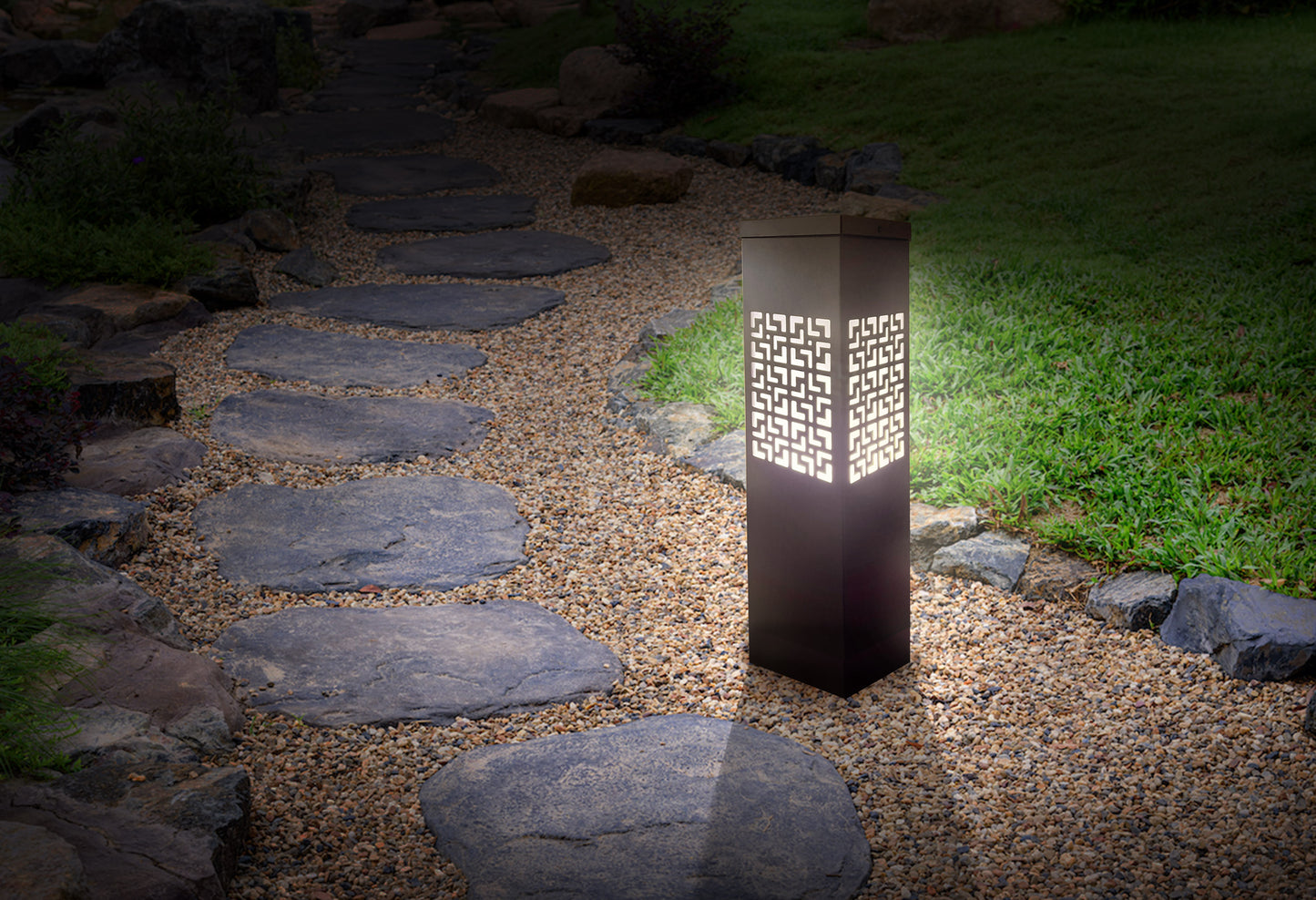 Alania Architectural Products outdoor lighting, garden light, with a geometric laser cut pattern. Installed in a landscape setting that illuminates a walkway.